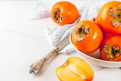 Delicious raw ripe persimmon fruit on white marble background copy space, kaki bon pour la sant&eacute;